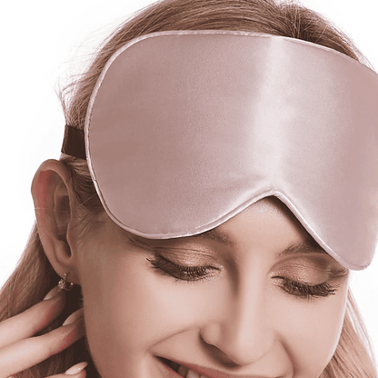 femme qui porte un masque de nuit en soie rose sur ses cheveux